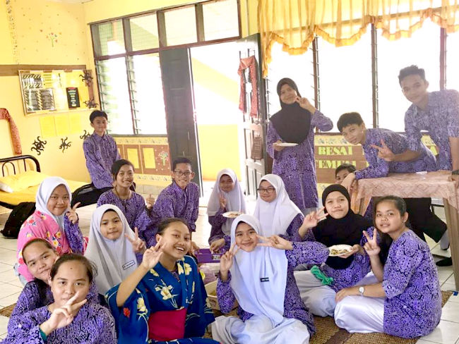 日本語パートナーズ マレーシア サラワク州 男子寮を訪れた女子生徒が男子生徒と一緒にお菓子を食べている写真