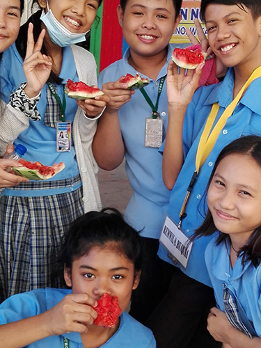 スイカ割で割ったスイカを食べる生徒たちの写真