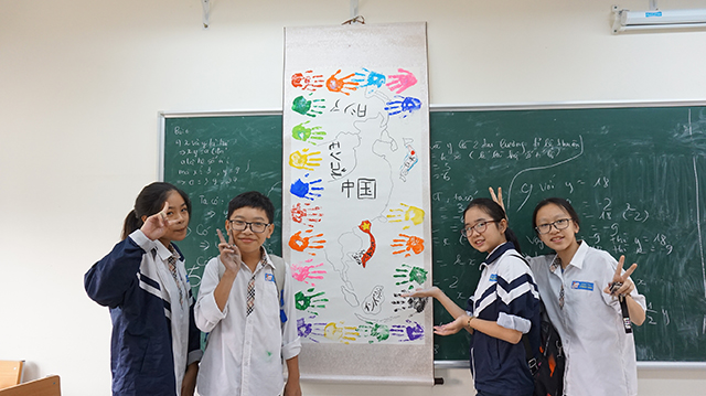 アジアのイラスト地図の周りに手形をつけた掛け軸と生徒たちの写真