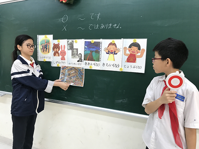 黒板に貼られたイラストと言葉で日本語を学ぶ生徒の写真
