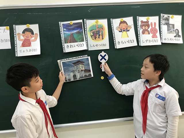 絵を掲げる生徒と、バツの表示をする生徒の写真