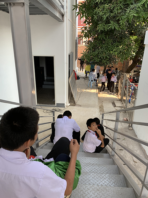 校舎の外階段で座る生徒たちの写真