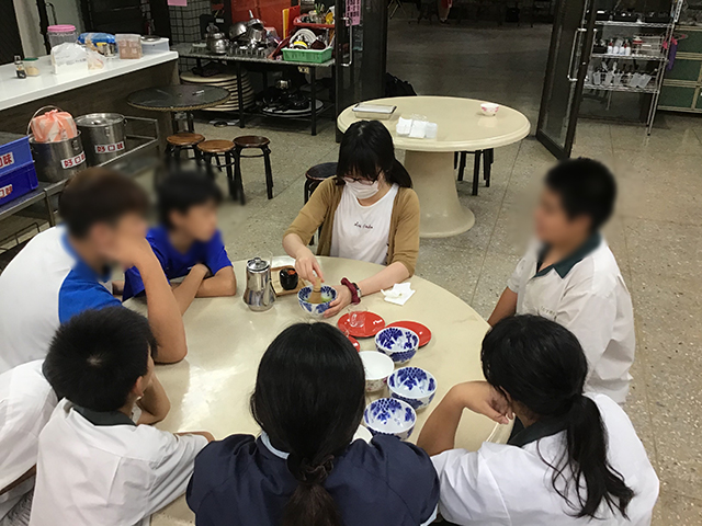生徒たちと座ったテーブルで抹茶をたてる川瀬さんの写真